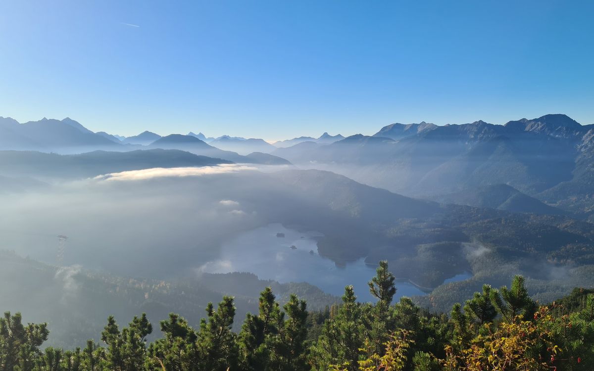 Blick über den Eibsee und das Nebelmeer auf die Bergketten