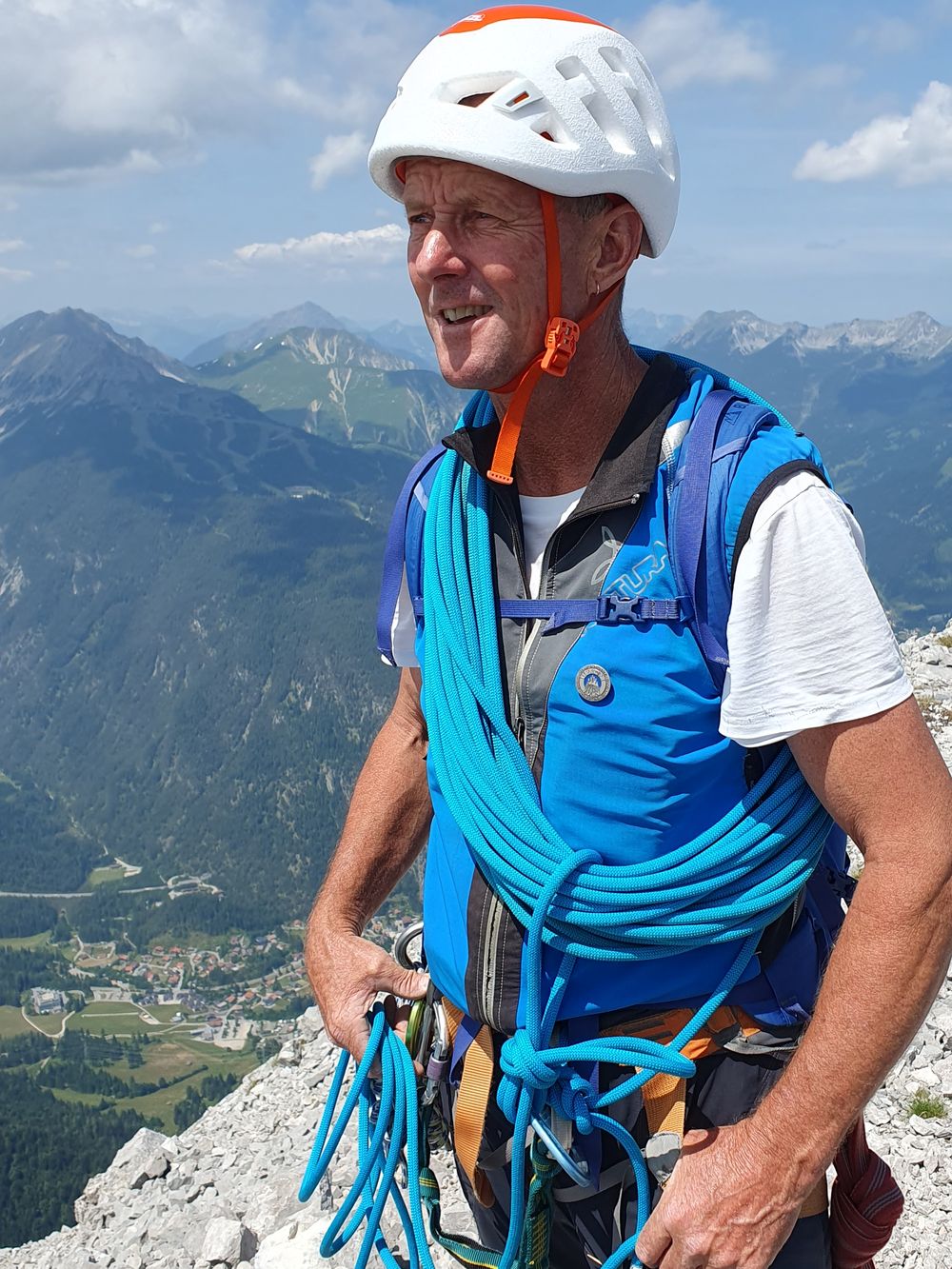 Robert Krinninger mit Helm und Seil am Fels, im Hintergrund das Tal
